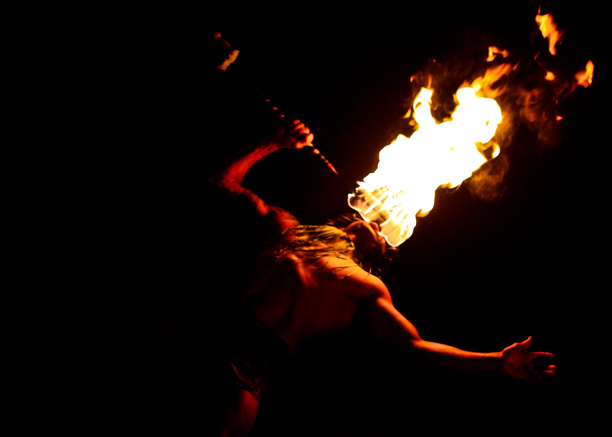 A fire knife dancer mid-spin against the dark