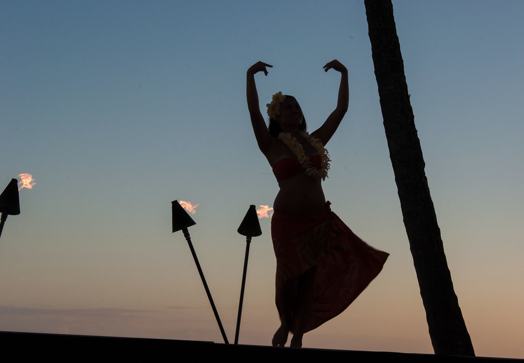 A dancer silhouetted beside lit torches after dark