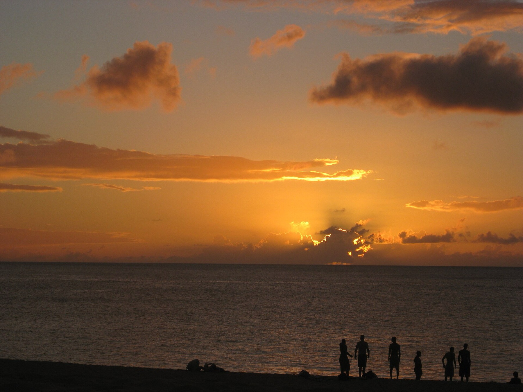 Guests gathering on the sand as the sun goes down